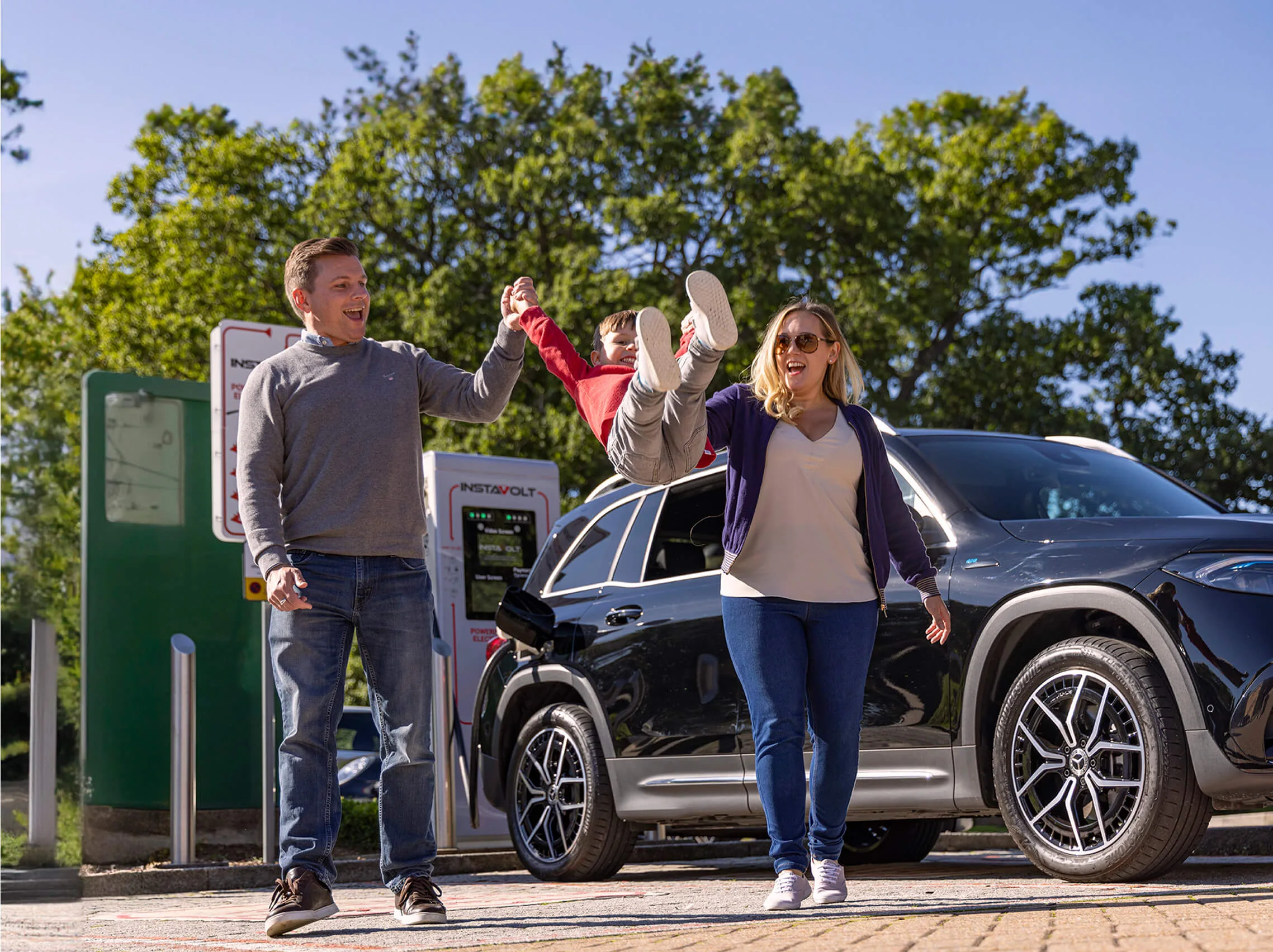 Mum and dad swinging child by car charging