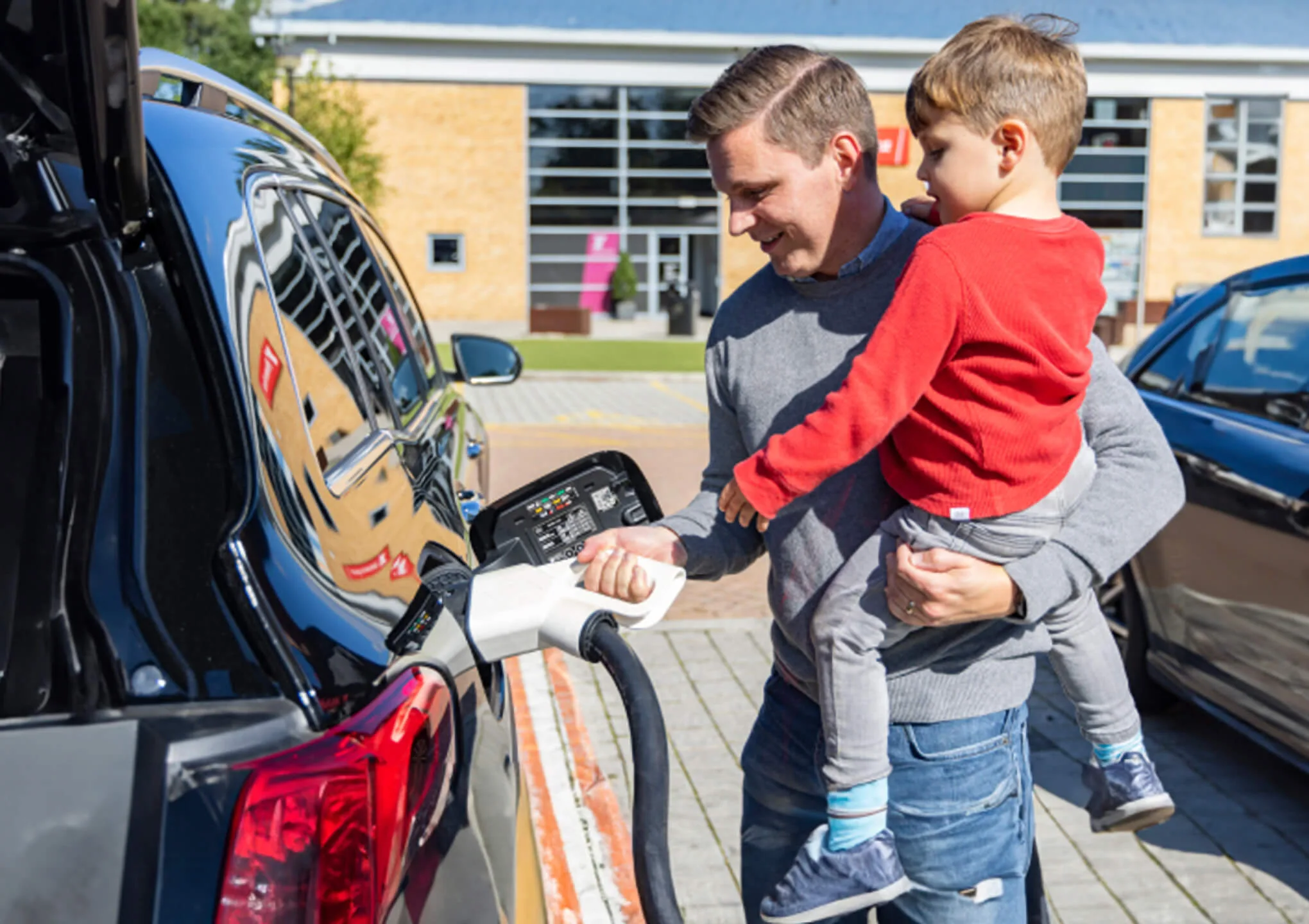 Man holding child charging car