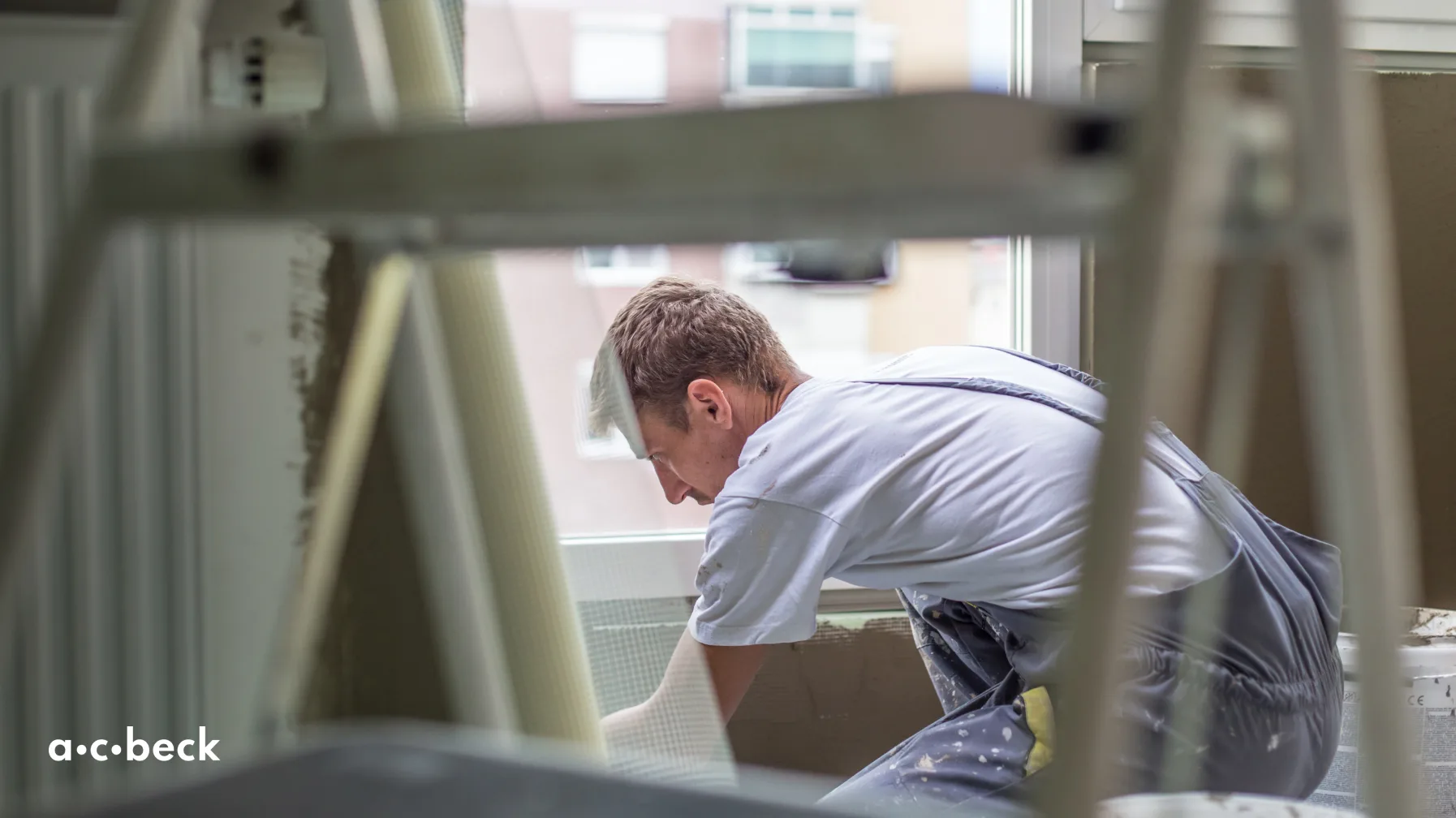 A man plastering a wall, shot through the steps ofa ladder