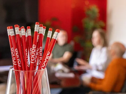 Glass cup full of Rouge red pencils.