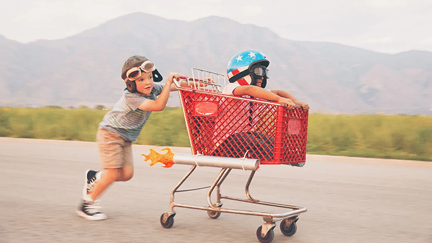Two boys in shopping trolley with helmets